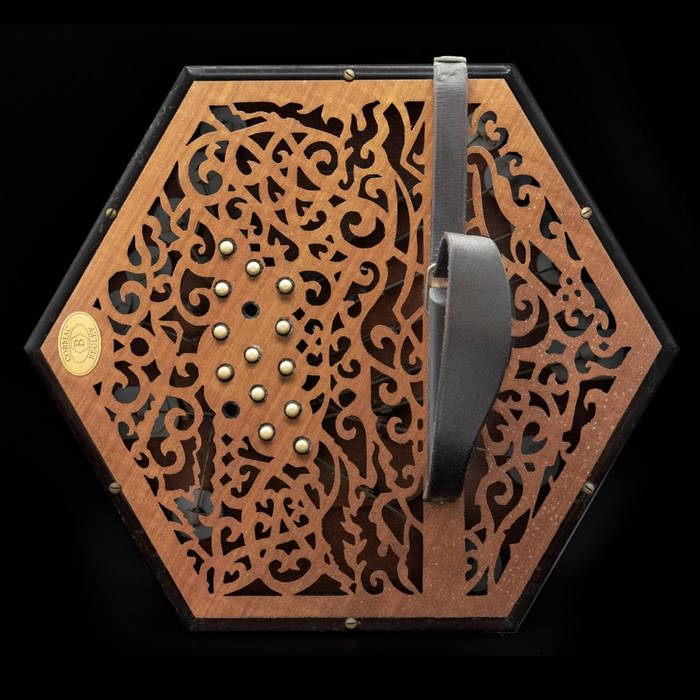 End view of a hexagon-shaped bass concertina, with finely-cut ornate wooden fretwork.